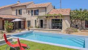 A two-story house with a swimming pool, red lounge chairs, and a stone facade. - Awesome home in Violes (Violes)