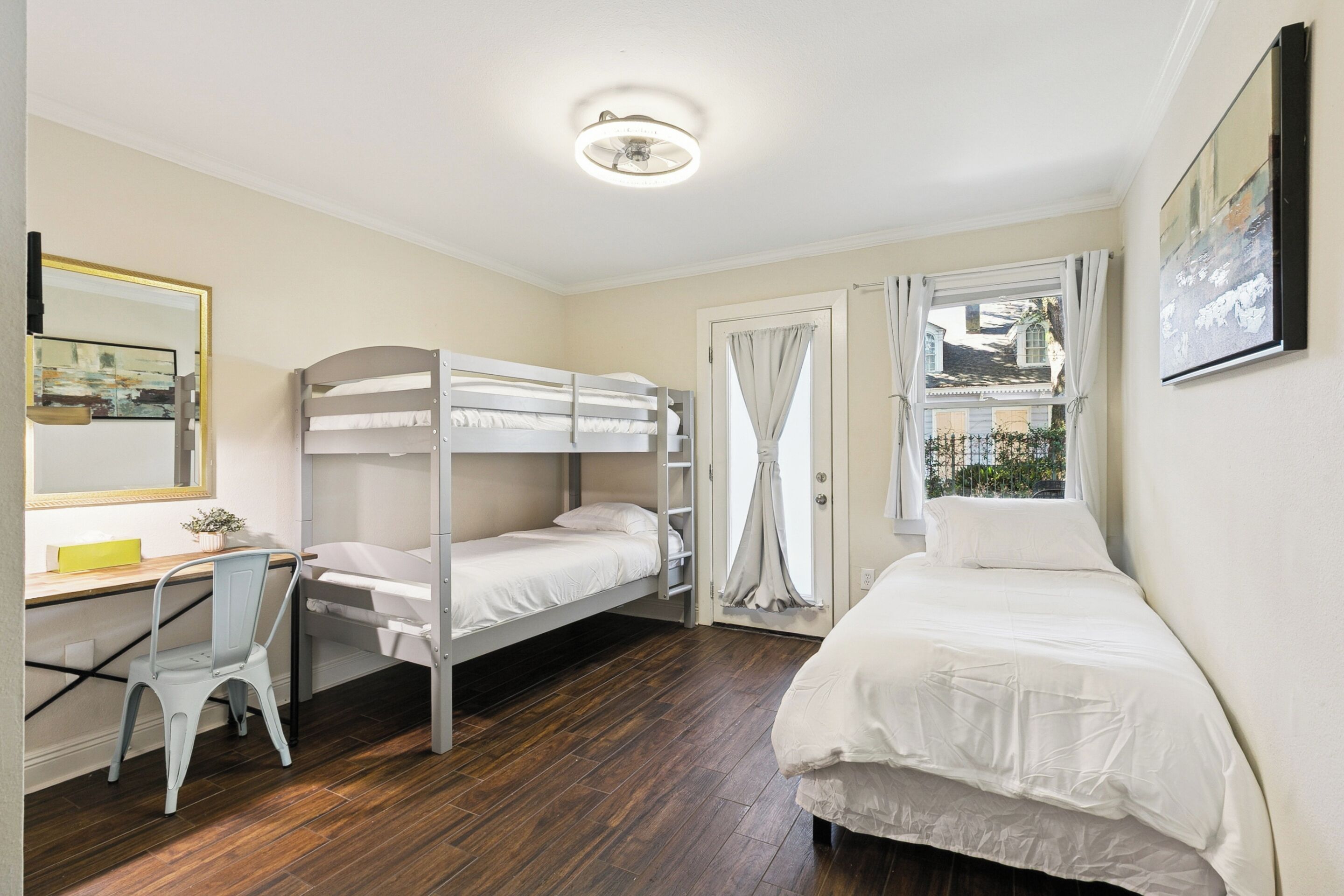 Ein Zimmer mit Stockbetten, einem Schreibtisch, einem Stuhl und einem Bett.