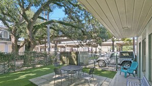 An outdoor patio with a table and chairs, a covered seating area, and a parked SUV.