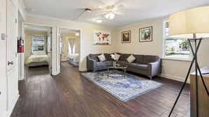 A spacious living room with a grey sofa, a coffee table, and a large window.