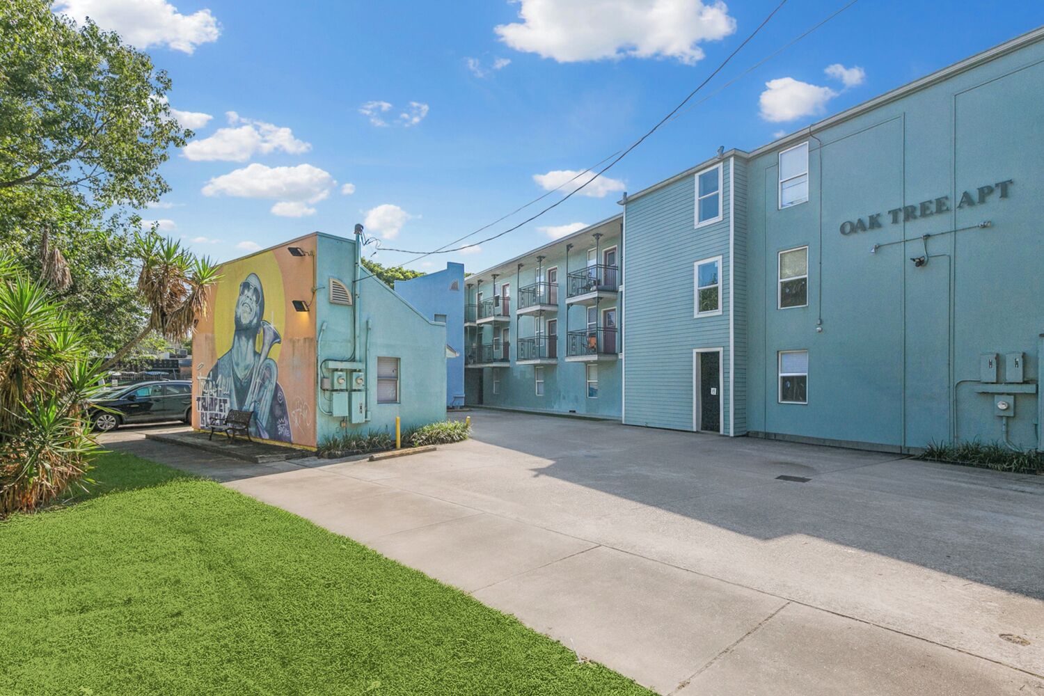 Un immeuble avec une fresque murale sur le côté gauche, portant l’inscription « OAK TREE APT. »