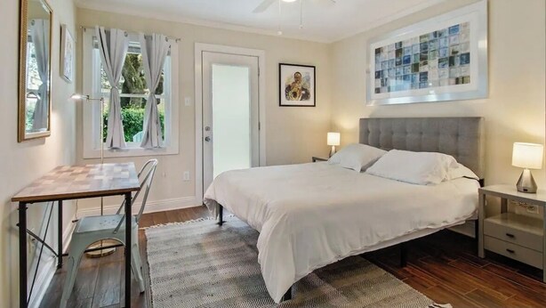 A bedroom with a bed, bedside tables, a desk, and a ceiling fan.