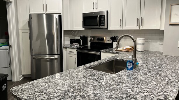 A modern kitchen with white cabinets, stainless steel appliances, and a granite countertop. - 5840 #312 Cozy but Accessible Hideaway. Lots of Amenities (Chapel Hill)