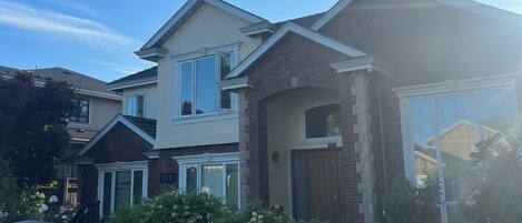 A two-story residential house with a brick facade, a garage, and a well-maintained lawn.