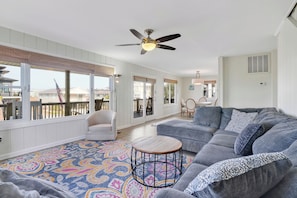 A spacious living room with a grey sofa, a round coffee table, and a ceiling fan. - Entire 5 Bed Room Beach House  (Carolina Beach)