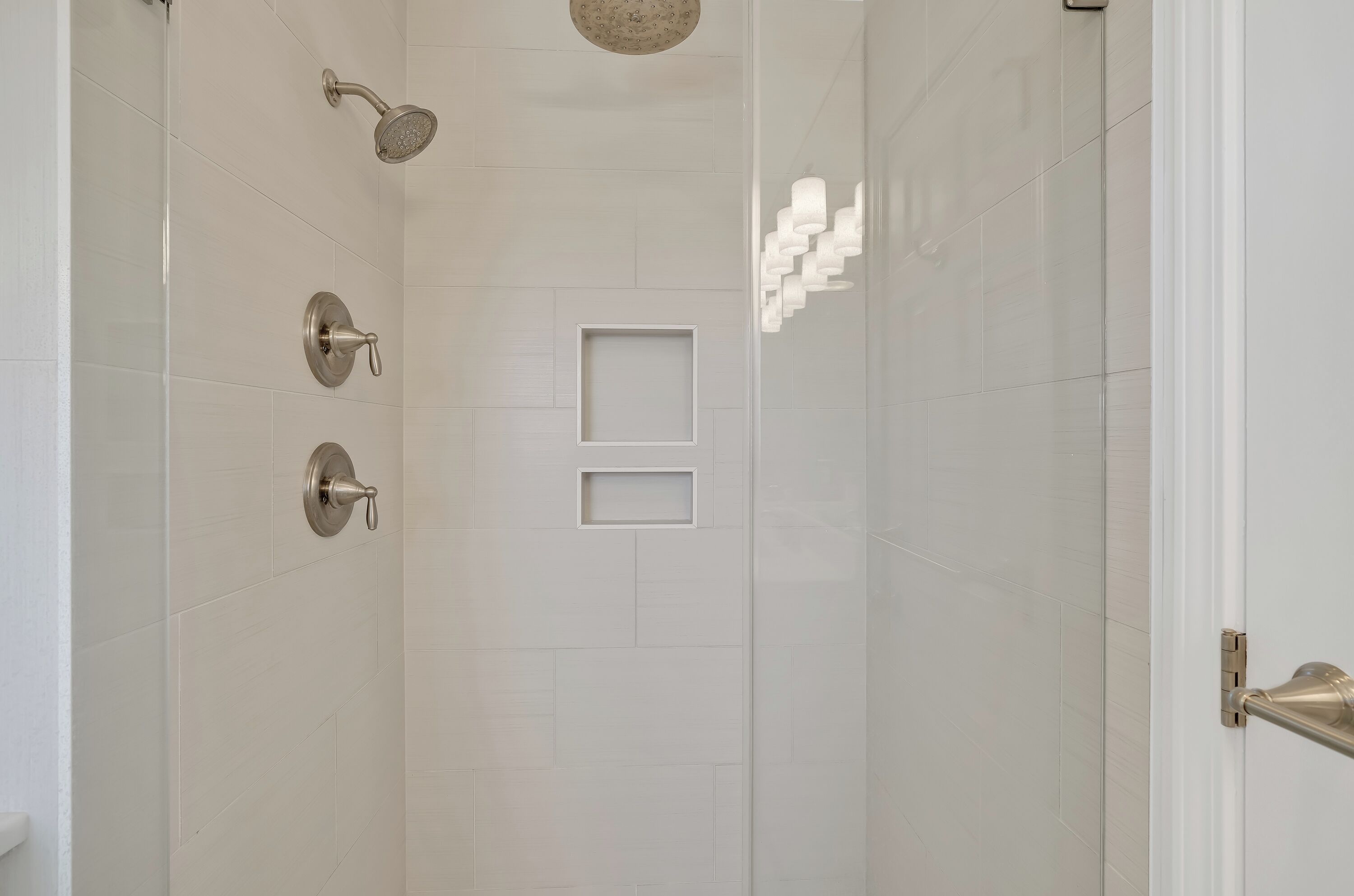 Une douche moderne dotée d’un pommeau de douche à main et d’un robinet mural.