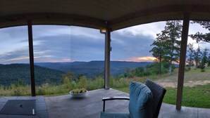 A covered outdoor seating area with a view of a mountainous landscape.