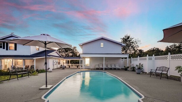 Ein Garten mit Swimmingpool, Liegestühlen und Sonnenschirmen.