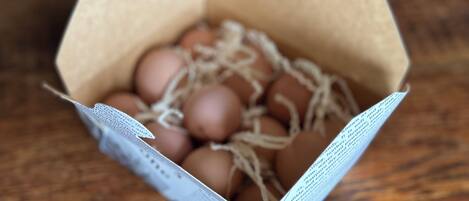A cardboard box containing brown eggs with straw.