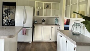 Eine moderne Küche mit weißen Schränken, einem integrierten Kühlschrank und Holzboden.