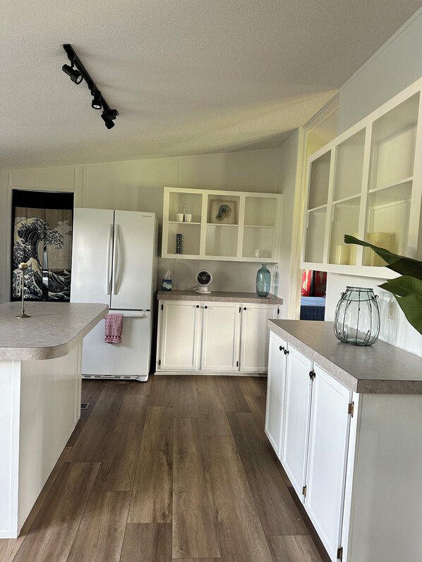 A modern kitchen with white cabinetry, a built-in refrigerator, and a wooden floor.