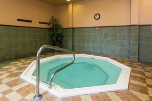 A hot tub with a metal ladder, surrounded by a checkered floor pattern, with a clock on the wall and a sign indicating a smoking area.