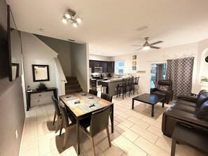 Cozy living space with a dining area, kitchen, and seating area, featuring a leather sofa and staircase.