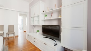 A modern living room with a flat-screen TV, white cabinetry, and a small potted plant.