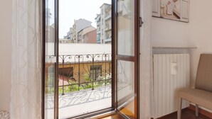A room with a large sliding glass door leading to a balcony with a metal railing.