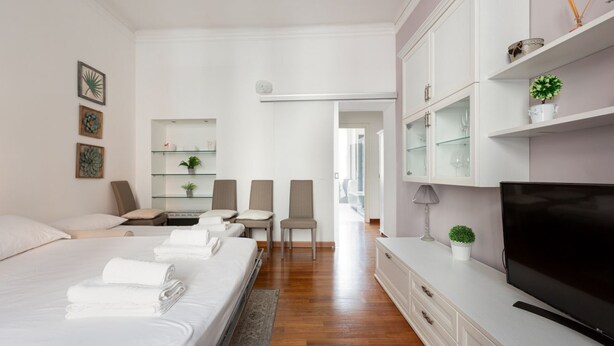 A modern hotel room with a bed, a TV, a desk, and a chair.