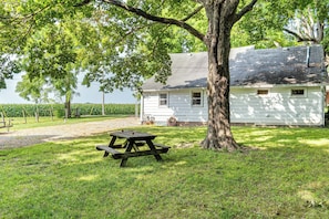 A white house with a large tree in front, a picnic table, and a cornfield in the background. - Peaceful Franklin Cottage ~ 1 Mi to Downtown! (Franklin)
