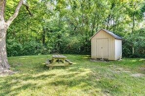 A wooden picnic table and a shed in a wooded area. - Peaceful Franklin Cottage ~ 1 Mi to Downtown! (Franklin)