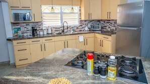 A modern kitchen with beige cabinets, a stainless steel refrigerator, a gas stove, and a microwave. - EcoMar Rentals #1: Cabo Rojo, Puerto Rico; Beach & Pool (Cabo Rojo)