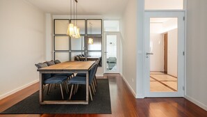 Un comedor moderno con una mesa y sillas de madera, un tapete negro e iluminación colgante.