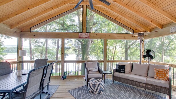 A covered outdoor seating area with a table, chairs, a sofa, and a fan.