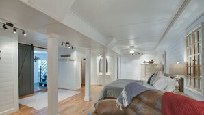 A bedroom with a bed, a leather sofa, a nightstand, and a dresser. There is a staircase leading to another room.