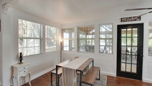 A room with a long table, benches, a small white desk, and a door with a sign.