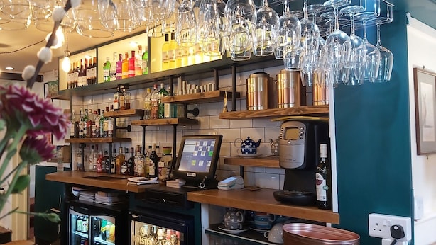 A bar area with shelves of liquor bottles, a cash register, and a refrigerated display case.