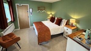 A bedroom with a bed, bedside tables, a chair, a dresser, and a radiator.