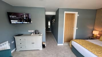 Une chambre d’hôtel avec un lit, un bureau avec une télévision, une porte et une lampe.