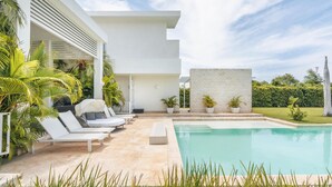 A modern poolside area with lounge chairs, a pool, and potted plants.