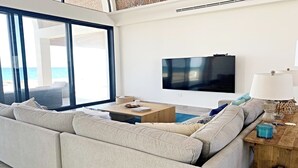A modern living room with a large sofa, a coffee table, and a TV mounted on the wall.