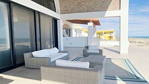 A modern outdoor seating area with wicker furniture and a view of the beach.