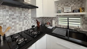 A modern kitchen with a gas stove, a coffee station, and a sink. - EcoMar Rentals #4: Near Beach Couple's Tropical Retreat (Cabo Rojo)