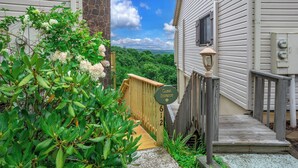 A guest entrance with a wooden deck leading to a house with a stone pillar and a view of a forested area. - Modern condo located in the resort village of Seven Devils. Great views! (Seven Devils)