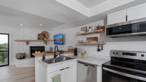 A modern kitchen with white cabinetry, a built-in oven, a microwave, and a dishwasher. - Modern condo located in the resort village of Seven Devils. Great views! (Seven Devils)