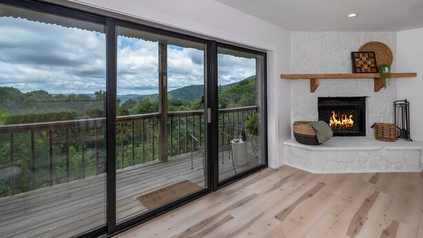 A spacious room with a large sliding glass door leading to a balcony, a fireplace, and a view of the countryside. - Modern condo located in the resort village of Seven Devils. Great views! (Seven Devils)