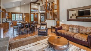 A spacious living area with a wooden staircase, a dining area, and a cozy seating area with a sofa and armchairs. - Golf View, Hot Tub, Suncadia Pool Access (Cle Elum)