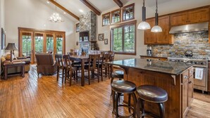 A spacious kitchen with a large island, wooden bar stools, and a stone fireplace. - Golf View, Hot Tub, Suncadia Pool Access (Cle Elum)