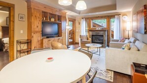 Een gezellige woonkamer met een open haard, een televisie en een eethoek.