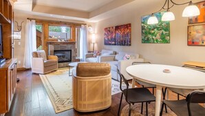 Een moderne woonkamer met een open haard, een eethoek en een gezellige zithoek.