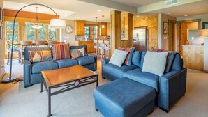 A spacious living room with a large sofa set, a coffee table, and a dining area with a chandelier. - Family Friendly w/ Suncadia Pool Access (Cle Elum)