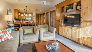 A cozy living room with a wooden TV stand, two armchairs, a sofa, and a coffee table. - Pet Friendly Condo, Suncadia Pool Access (Cle Elum)
