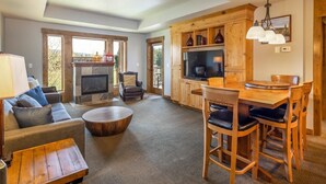 Amplia sala de estar con chimenea, una mesa de comedor con sillas, un sofá y un televisor.