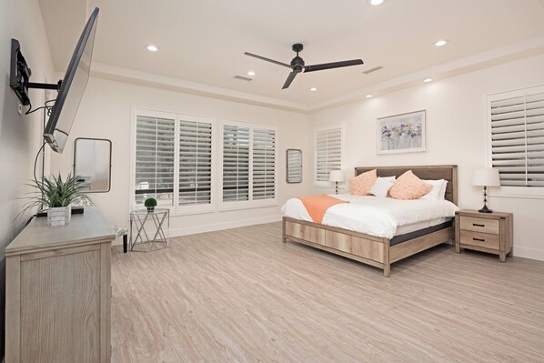 A bedroom with a bed, bedside tables, a ceiling fan, and large windows with blinds. - Luxury Resort Style Living w/ Pool & Jacuzzi (Indio)