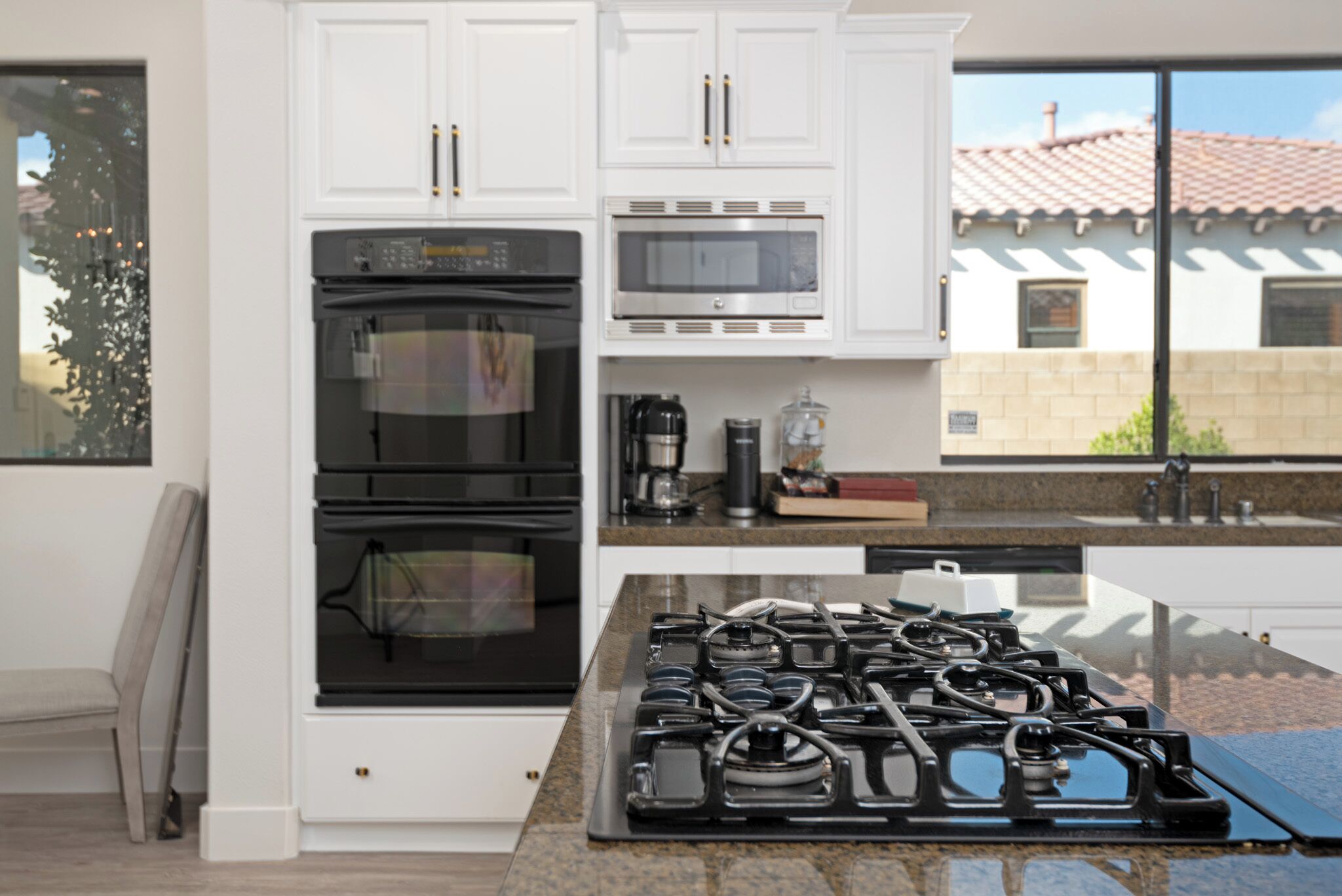 A kitchen with white cabinets, a double oven, a microwave, and a gas stove.
