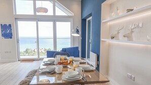Ein Essbereich mit einem Glastisch, weißen Tellern und Blick aufs Meer.