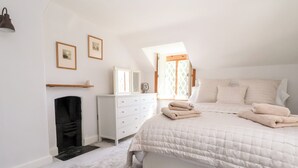 Quarto com cama, cômoda, espelho e lareira.