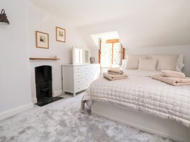 A bedroom with a bed, a dresser, a mirror, and a fireplace.
