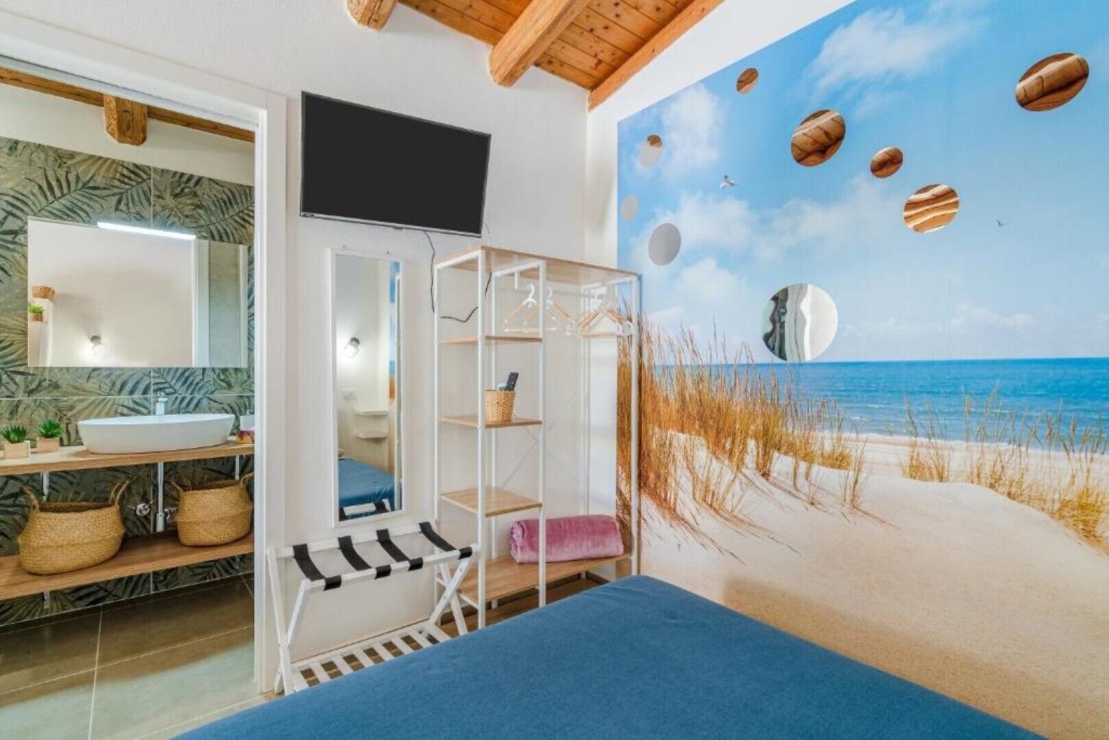 Una stanza con un murale a tema spiaggia, un lavandino bianco e un soffitto in legno.